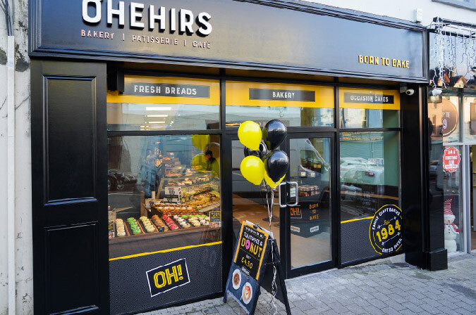 A Shopfront Of O'Hehir's Bakery With Cakes And Donuts In The Window